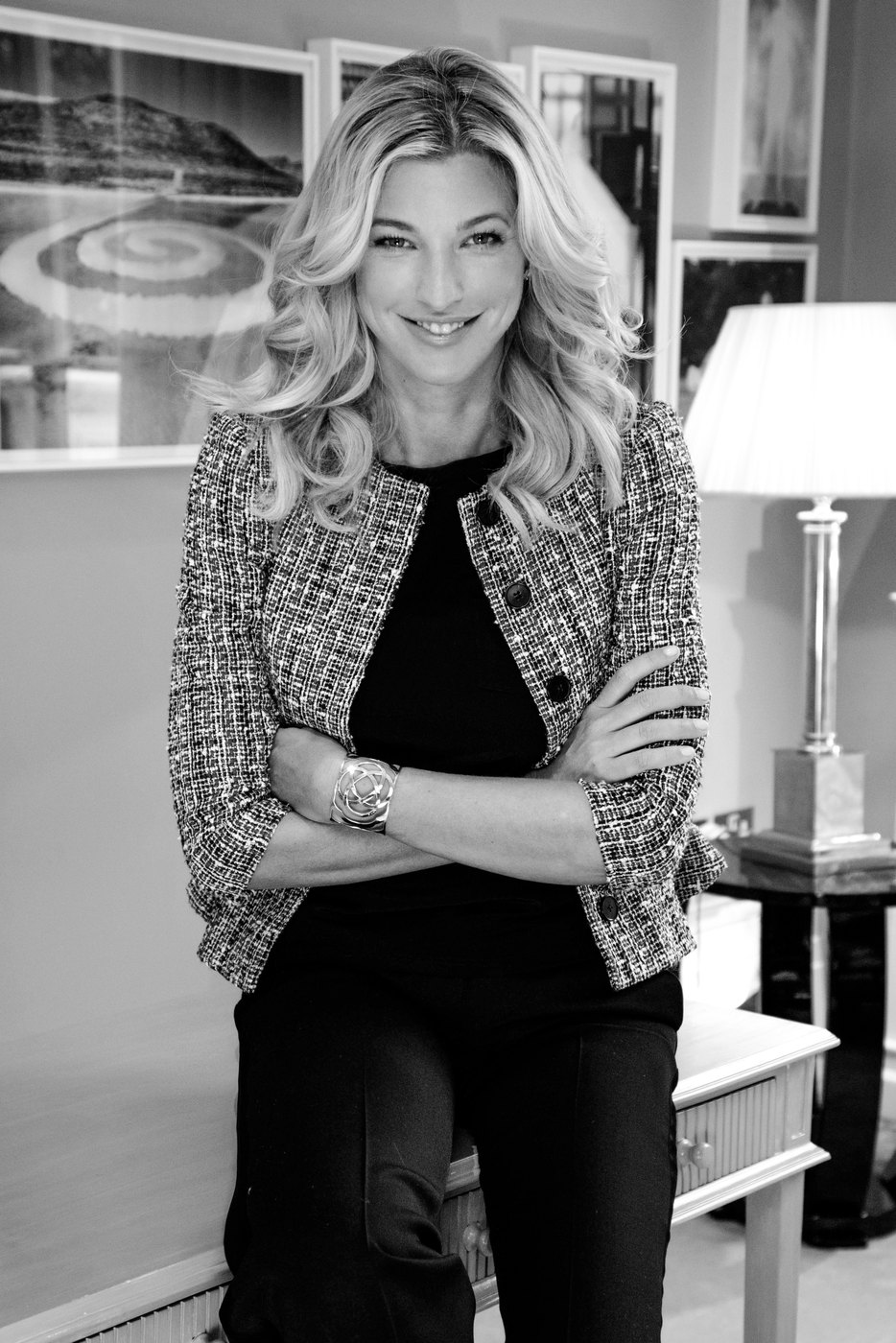 Nicole Brachetti Peretti smiling in a tweed jacket in a softly lit room, in black and white